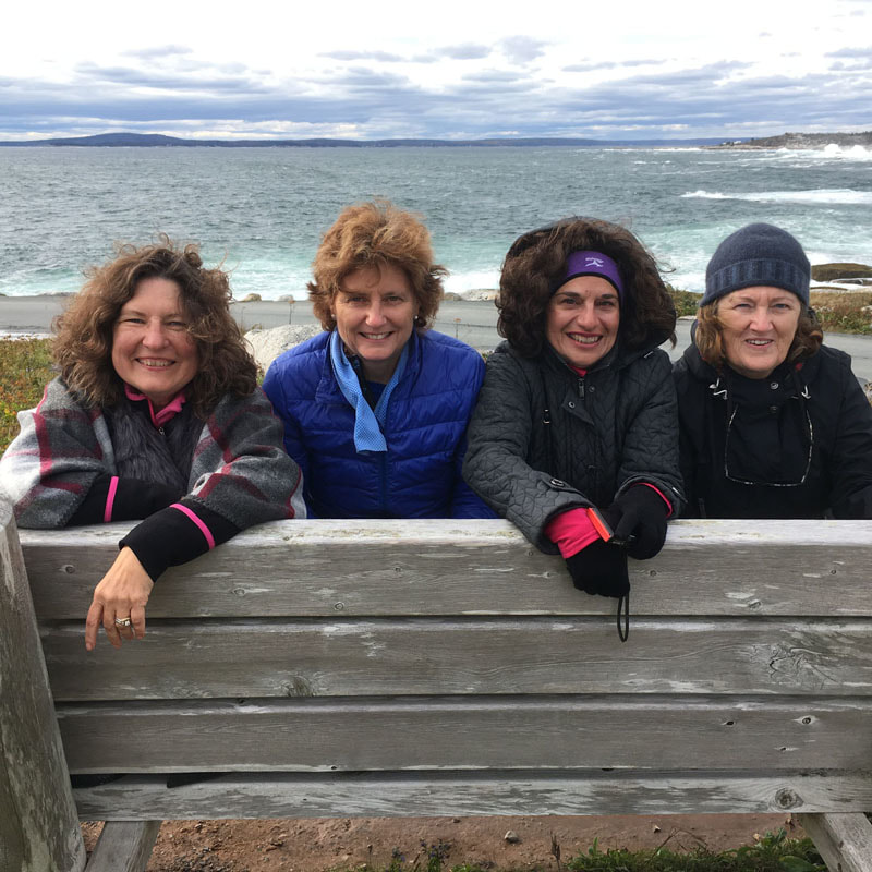 Tourists posing on a bench at Peggys Cove lighthouse.